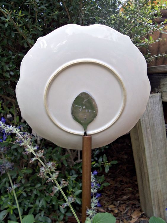 example of a way to attach garden art flowers to the post by gluing a spoon on backside of plate and sticking it inside the hollow post