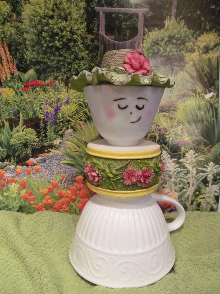 a garden lady figure made out of tea cups