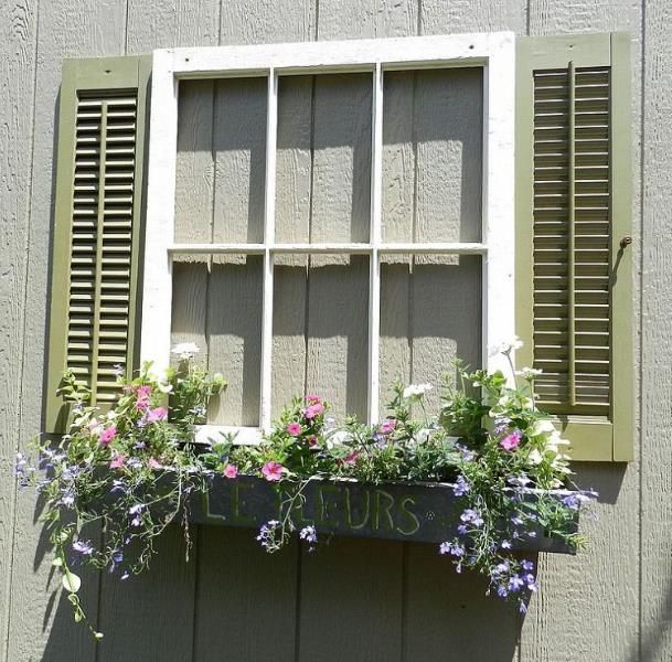 a window frame without the glass attached to a storage shed to make it look like a real window.