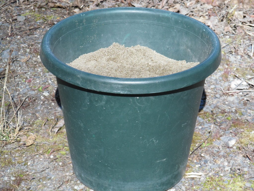 green plastic planter filled with sand to support ad display  the dish flower stake