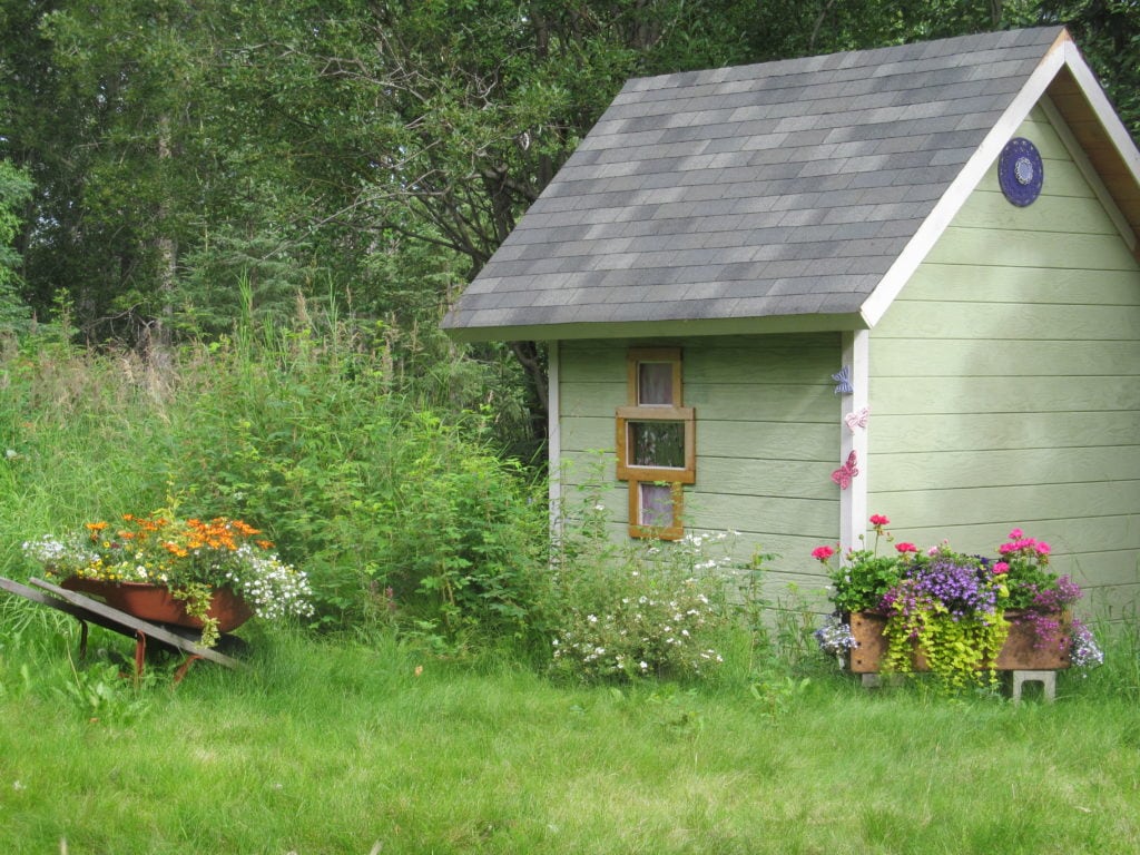 Author's garden shed and the front lawn with planters full of bright flowers