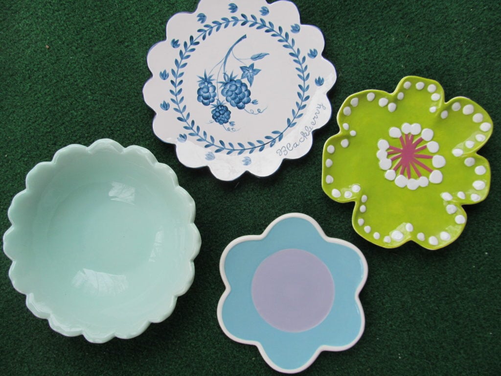 plate flowers. 4 ceramic dishes that are shaped like flowers and have scalloped edges.