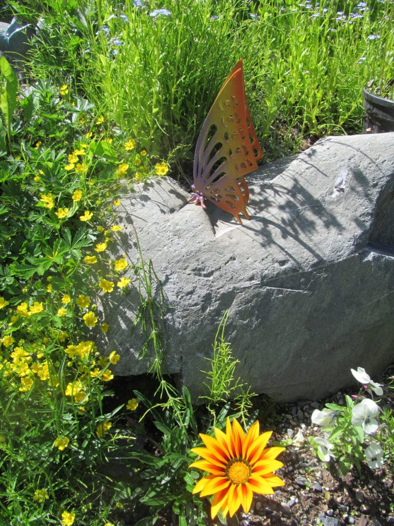 brass butterfly on rock in garden after spray paint garden art
