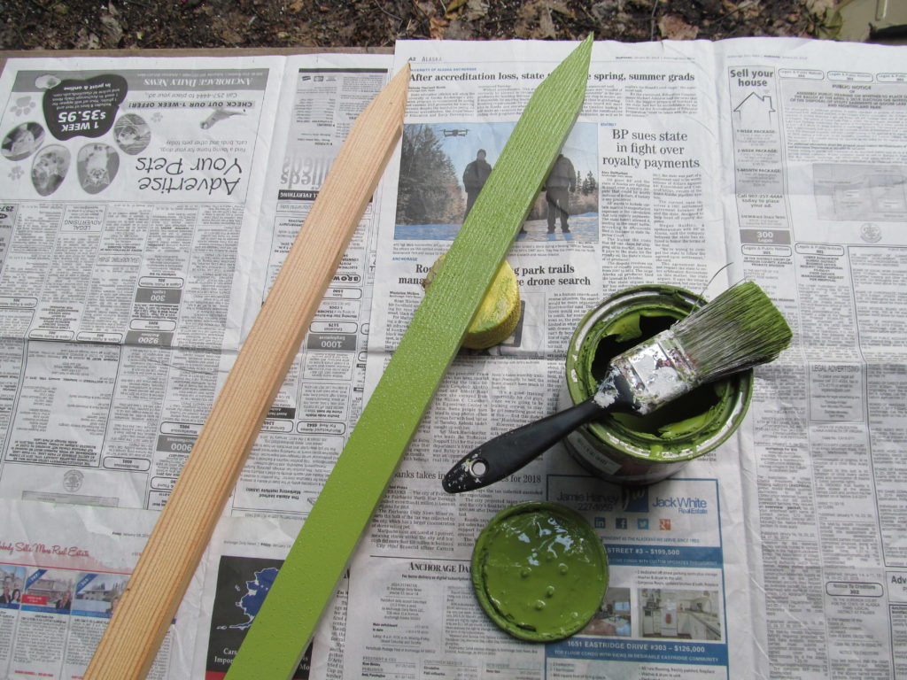 Plastic dishes make cheerful flowers: Photo: image of two wood stakes and a can of green paint and paint brush to paint the wood like a flower stem