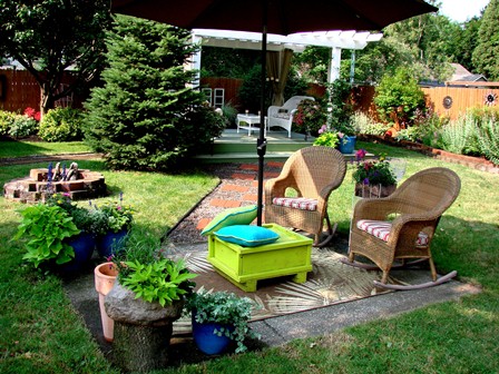 Picture of a nice backyard with a lawn, a few shade trees and a pathway made of paver style bricks. The pathway leads to a small sitting area with comfy chairs and umbrella for shade. Its one of the look you love for the garden.