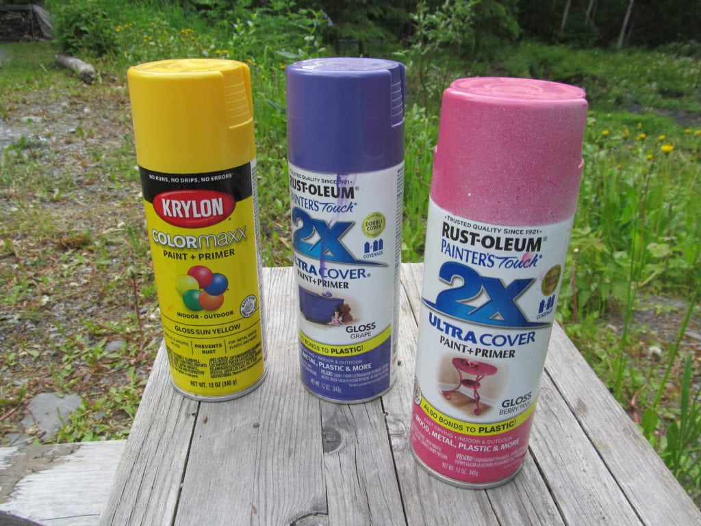 3 cans of spray paint outside on a bench