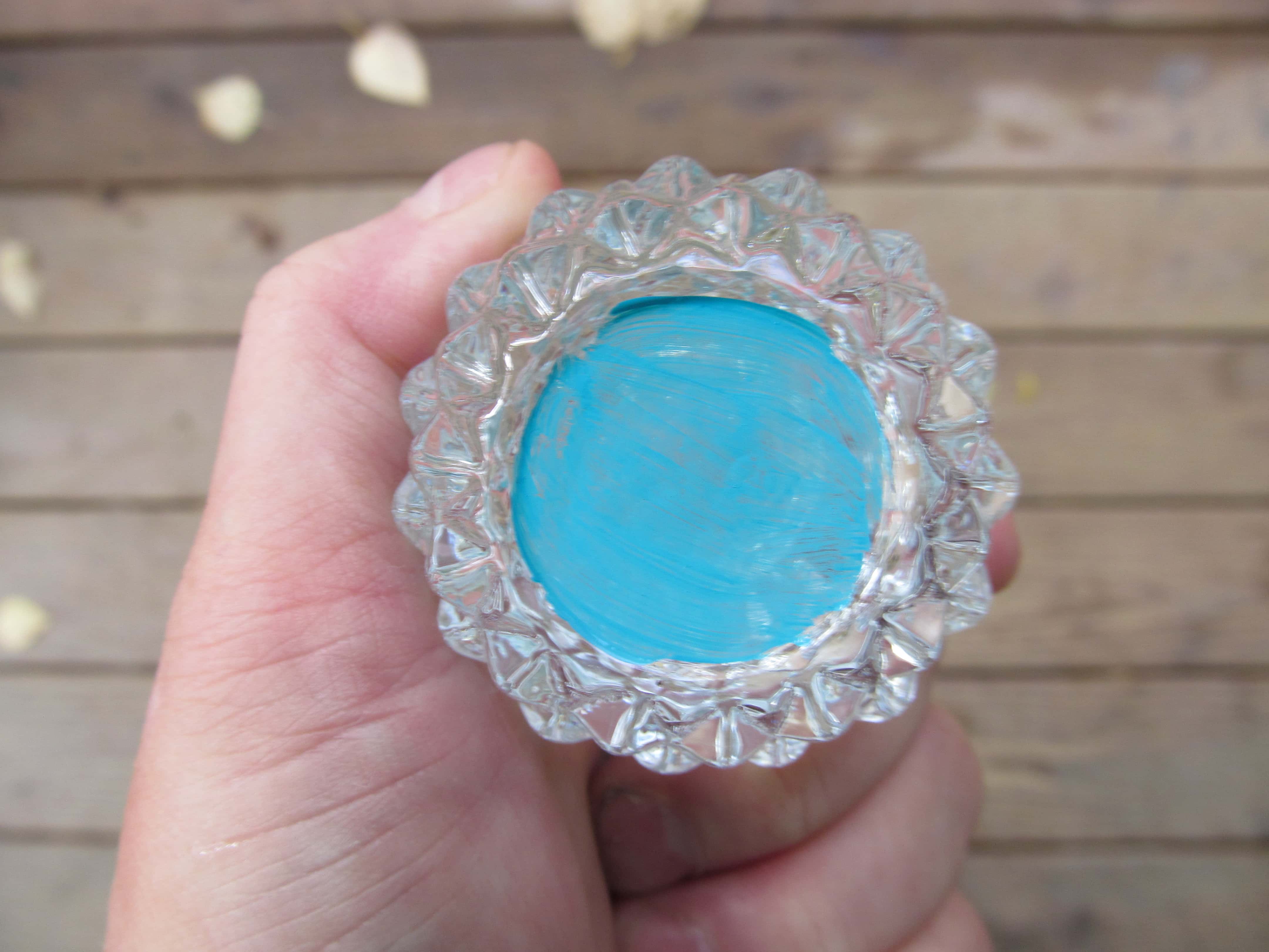  Gemalter Boden eines Kerzenständers aus geschliffenem Glas mit blauer Farbe. Es reflektiert die Farbe auf dem ganzen Glas, wodurch das klare Glas natürlich blau aussieht.