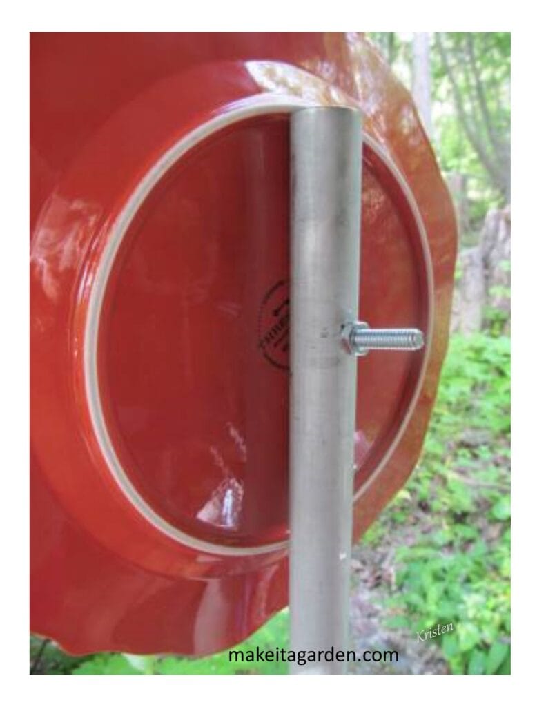 shows the backside of a plate with a bolt thru the center and the bolt inserted through a hole in a hollow metal post so the whole dish flower is attached to the post.