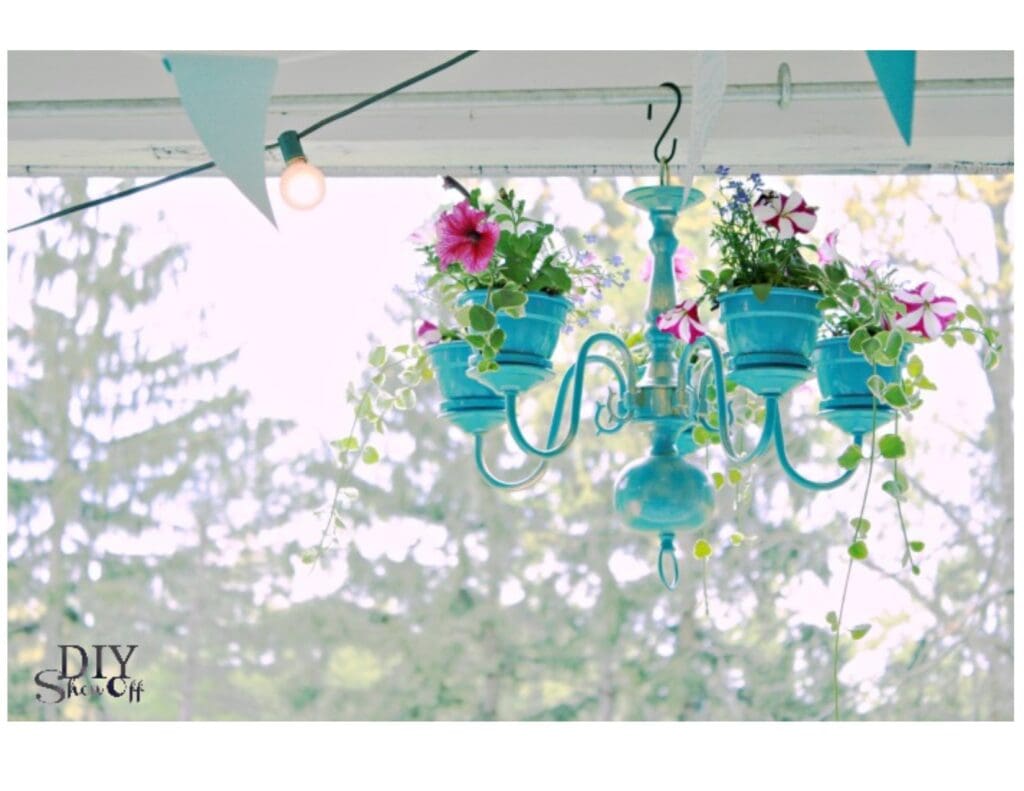 Garden design trends of 2020 shows a dining room chandelier painted bright blue and instead of lights, there are flower pots with petunias.  The chandelier hangs outside on the patio.
