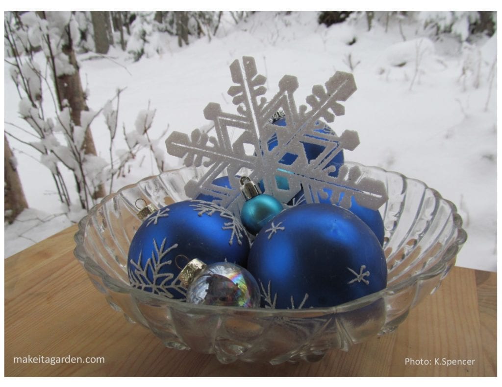 Christmas tree balls displayed in a pretty clear glass bowl with a plastic snowflake for decor