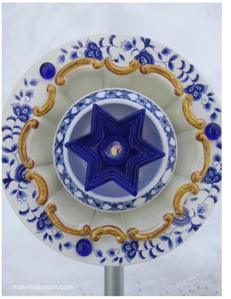 garden art flowers made from ceramic plates. Blue and white pattern with gold trim and blue star in center