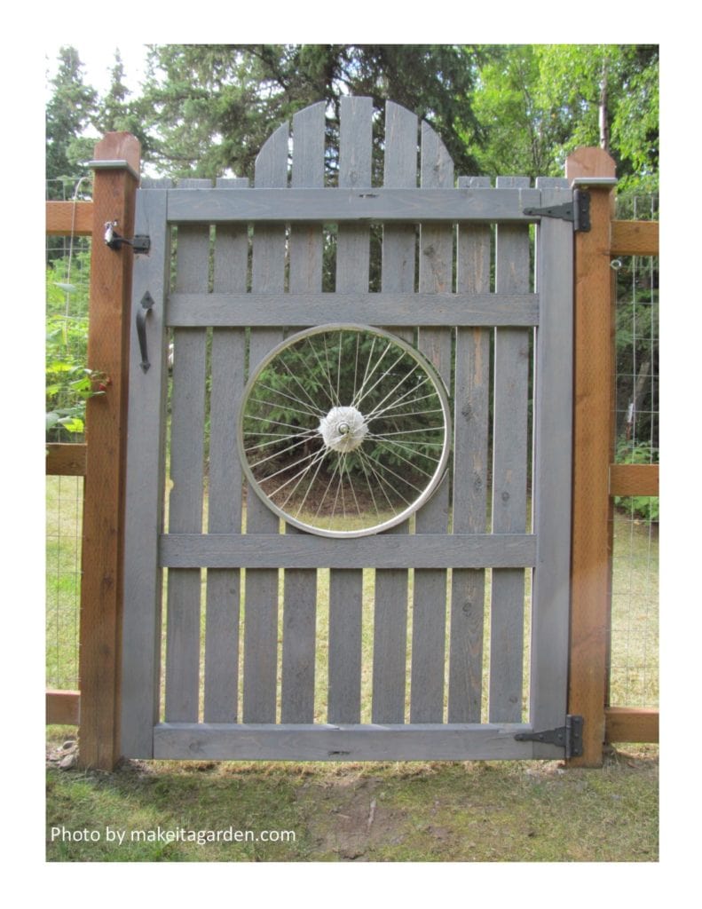 Wooden Gate with a bicycle wheel in the center. Artistic way to improve a wood fence in the backyard