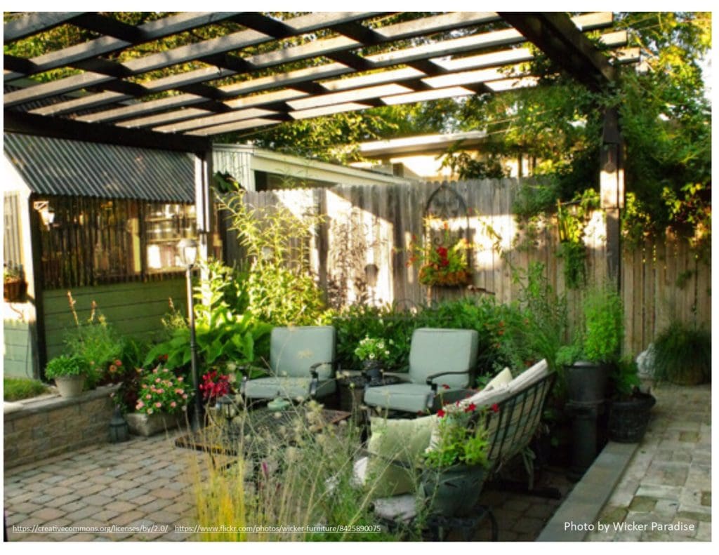 Garden theme semi-formal. Photo of outdoor patio with a pergola overhead. chairs and couch around a coffee table. Nice seating area.
