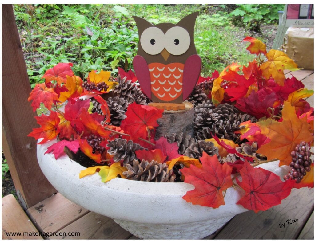 Planter filled with leaves and pine cones with owl in the center. Decor for Pretty Fall porch