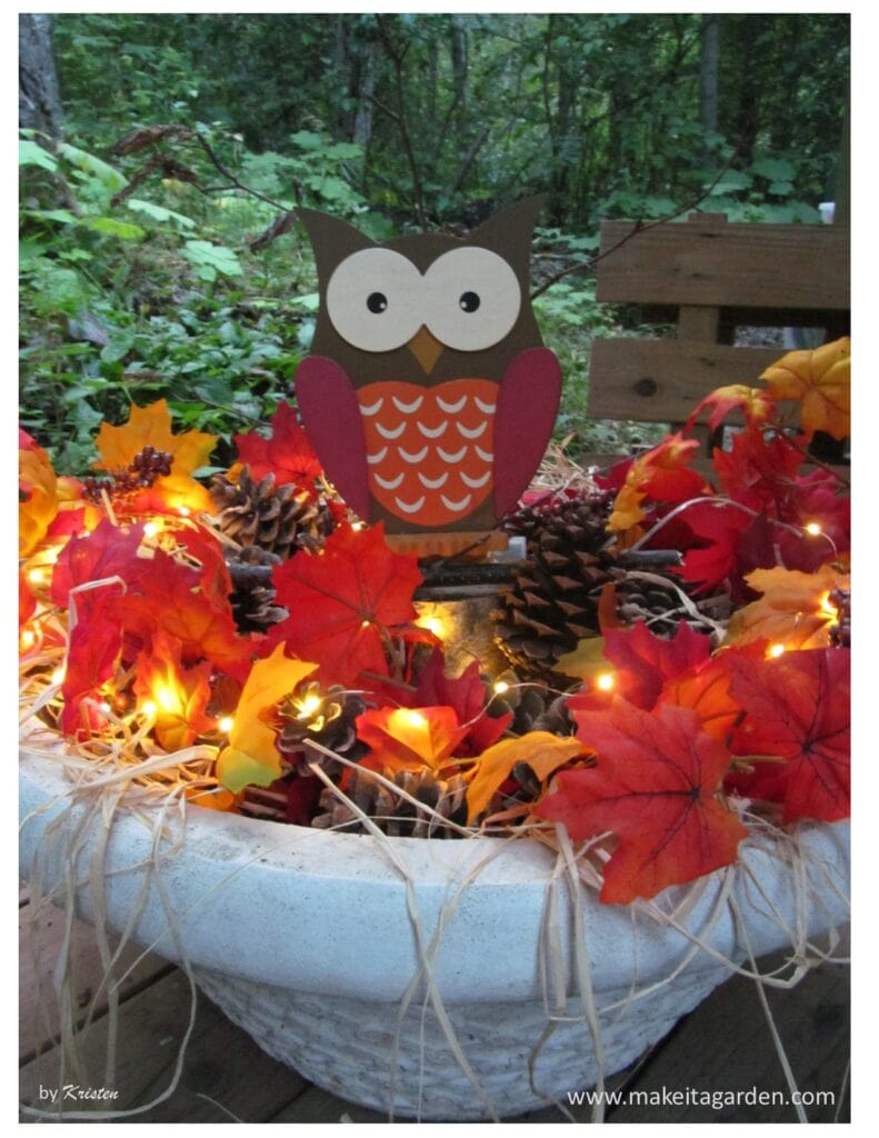 decor for pretty fall porch. Photo of planter filled with fall decor like leaves pine cones mini lights and owl centerpiece