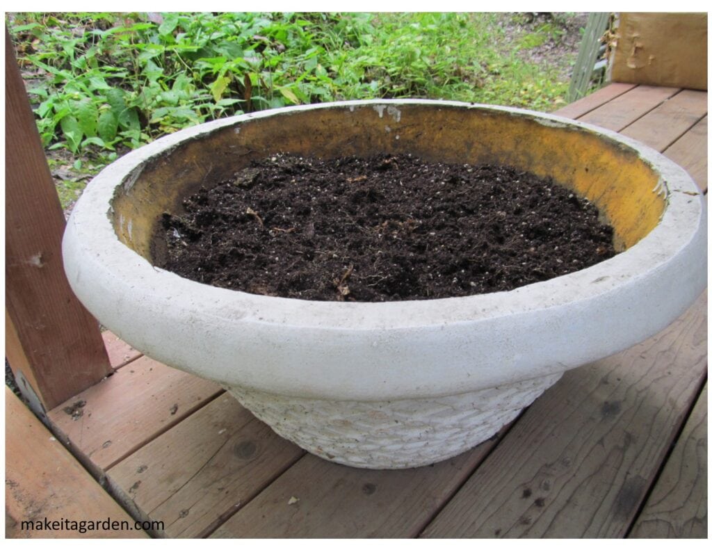 a large, round flower planter with dirt in it on the front porch
