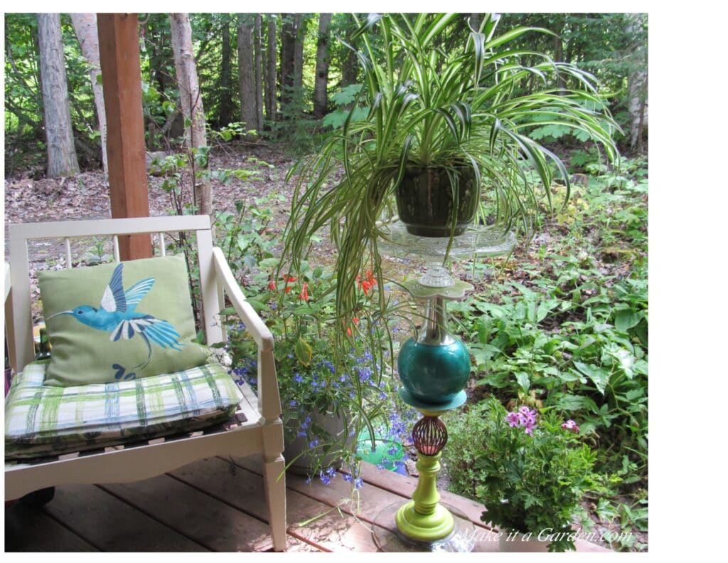 plant stand with large, sprawling plant on top is out on the porch next to a chair.