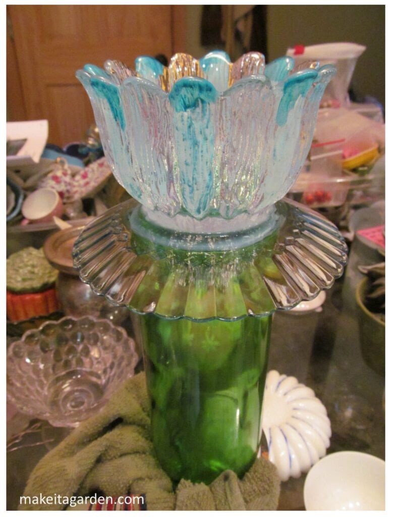 photo of a glass flower shaped cup attached by glue to the wine bottle