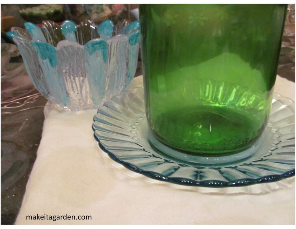 Close up shows bottom of wine bottle attached to a glass saucer