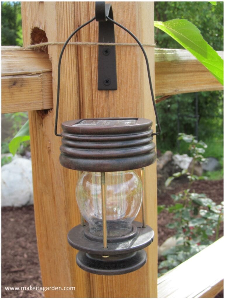 close up of a solar lantern hanging on the fence. Lights up the fence at night