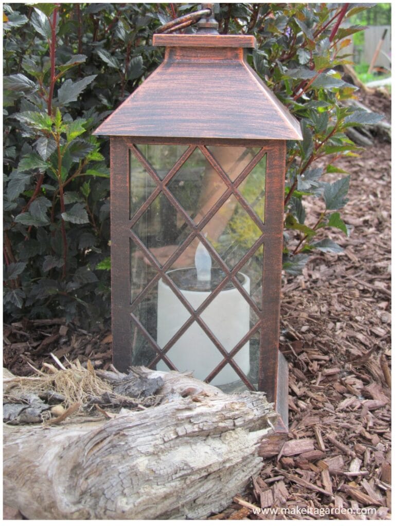 close up of a candle lantern in the garden with a fake battery candle flame on the inside. Lights up garden at night