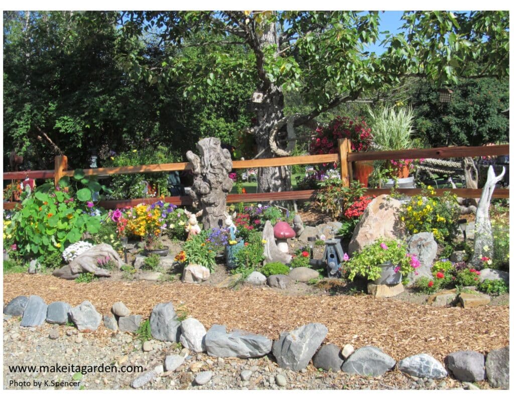 View of the garden from the street. Split rail wood fence with lots and lots and lots of flower baskets and flower beds and rocks to line the border.