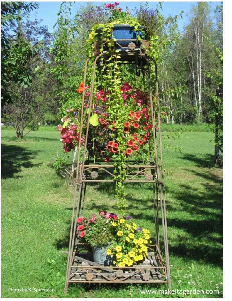 baskets and planters of flowers on 3 levels of a tall garden tower planter