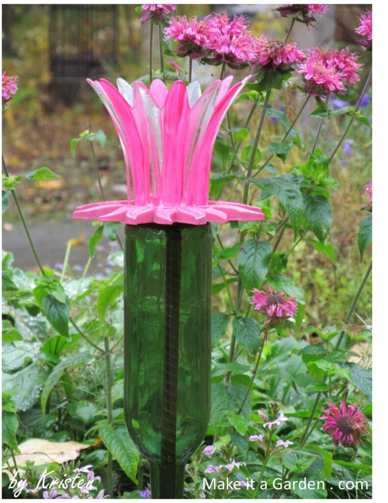Wine Bottle flowers displayed in the garden around real flowers as an art piece.