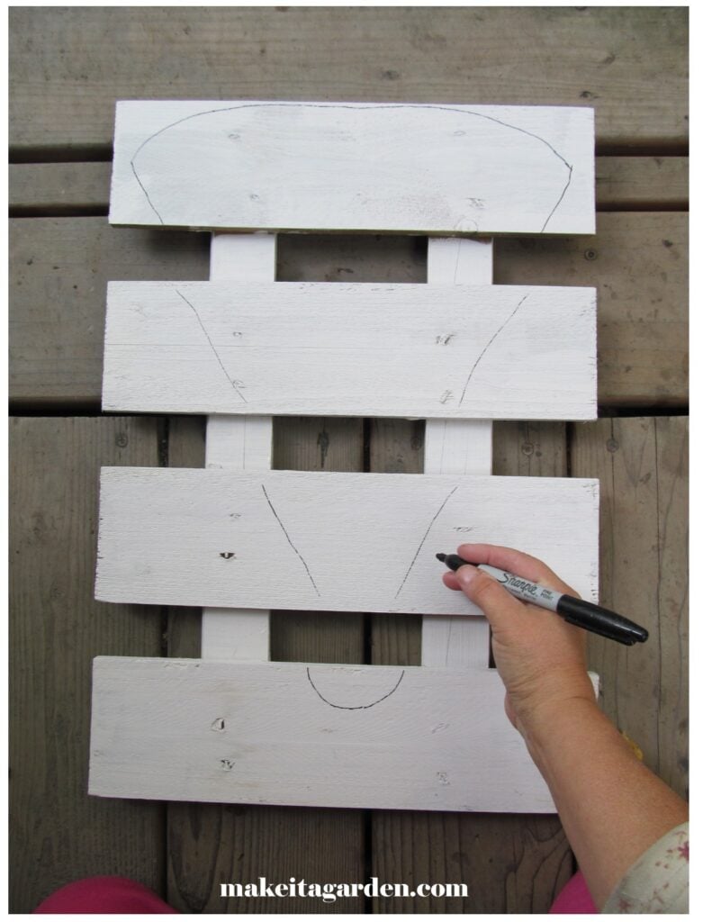 crafter drawing the outline of reindeer face on a the pallet to make wood pallet reindeer