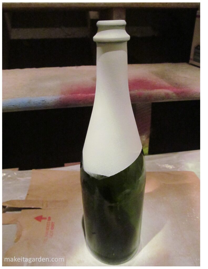 Glass bottle after the neck of the bottle is spray painted white. When dry it will be yarn wrapped wine bottle