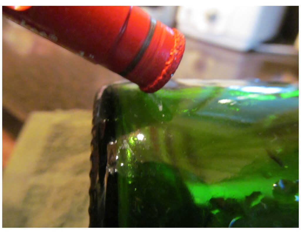 a close up showing the drill tip at a 45 degree angle on the bottle