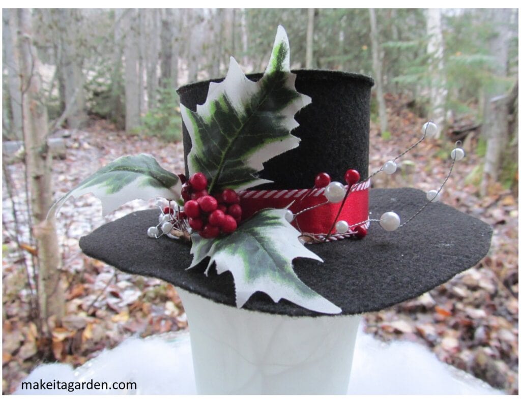 Felt snowman top hat decorated with red ribbon and holly sprig