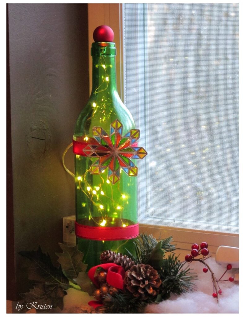 Green wine bottle decorated for Christmas with little mini lights on the inside. Drill a hole in a wine bottle