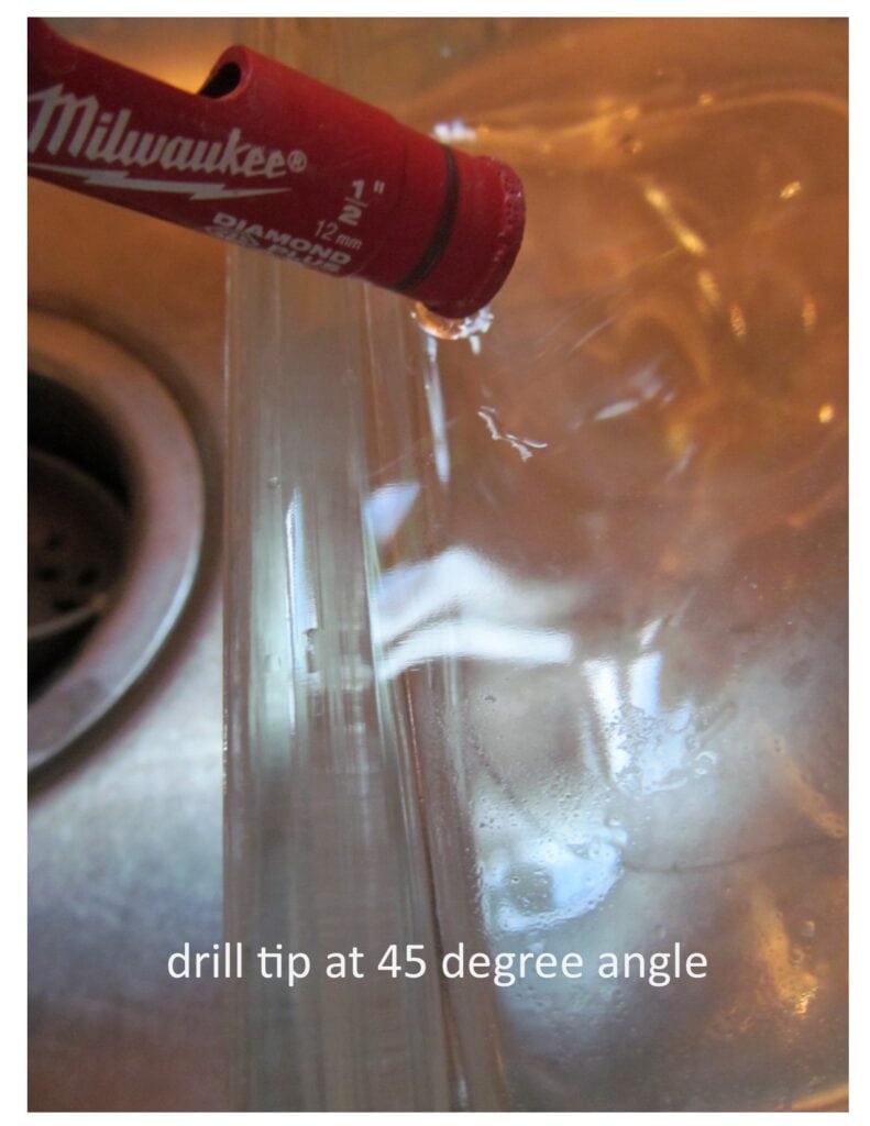 Close-up of the drill bit at a 45 degree angle on the glass block to demonstrate how to make the hole