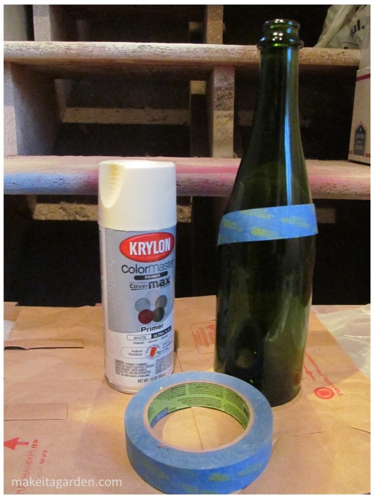 preparing to paint a wine bottle. Bottle, spray paint and painter's tape in a group