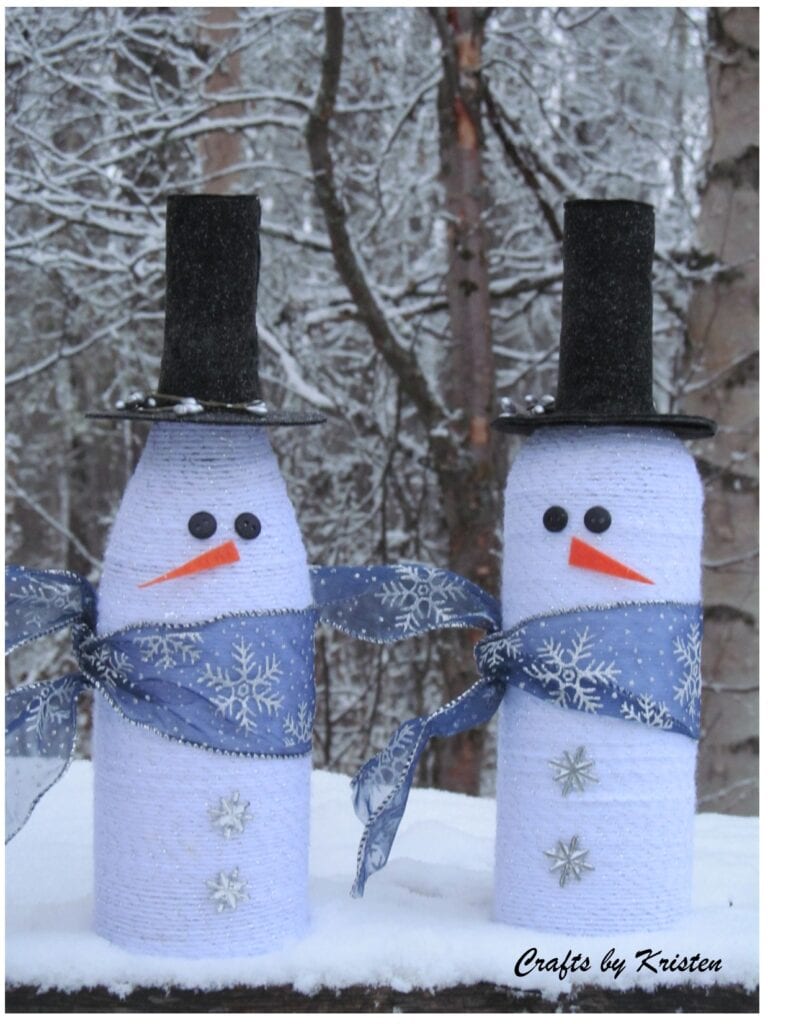 Two wine bottles wrapped with white yarn and decorated to look like snowmen. A different way to decorate a wine bottle for Christmas