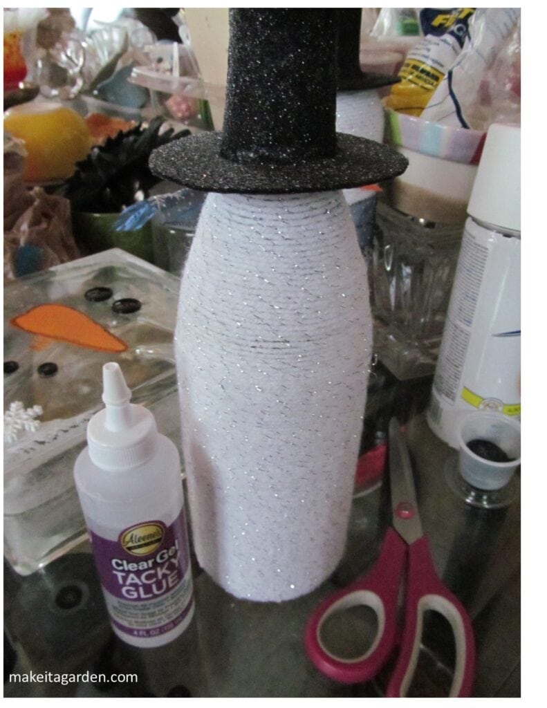 The felt hat pattern is cut out and glued in place over the neck of the wine bottle