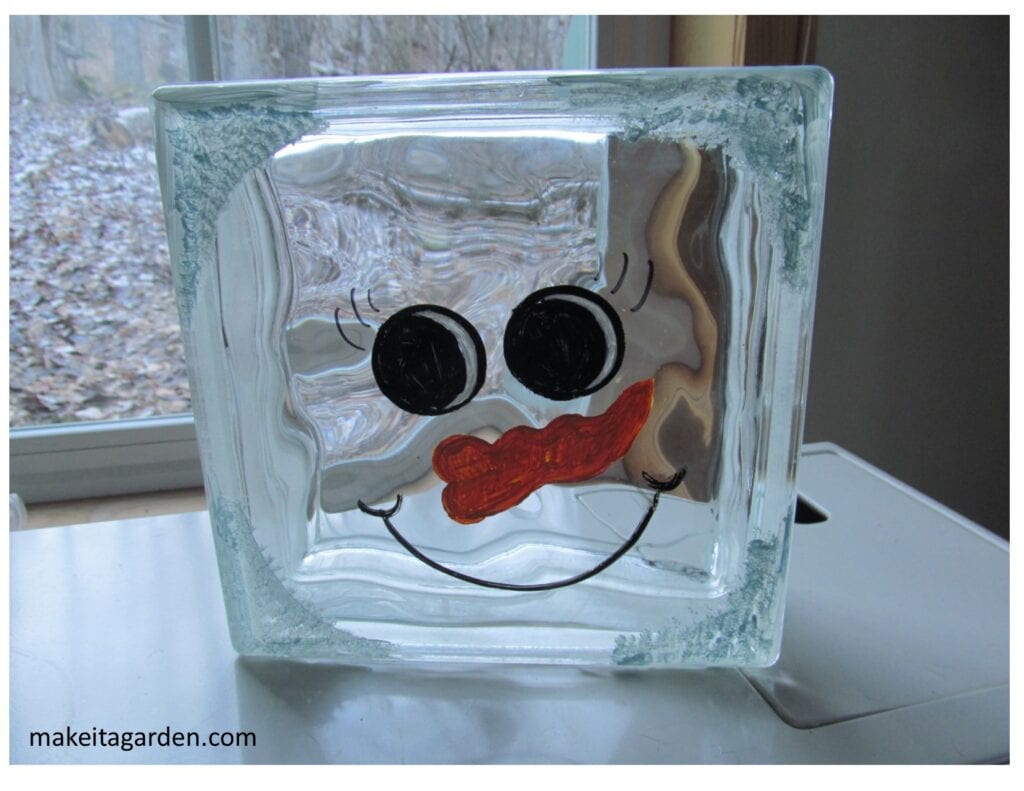 a cute face expression painted on a lighted glass block snowman
