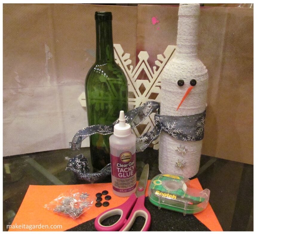 Various craft materials gathered together on the kitchen table. Wine bottle, buttons, glue, scissors, felt