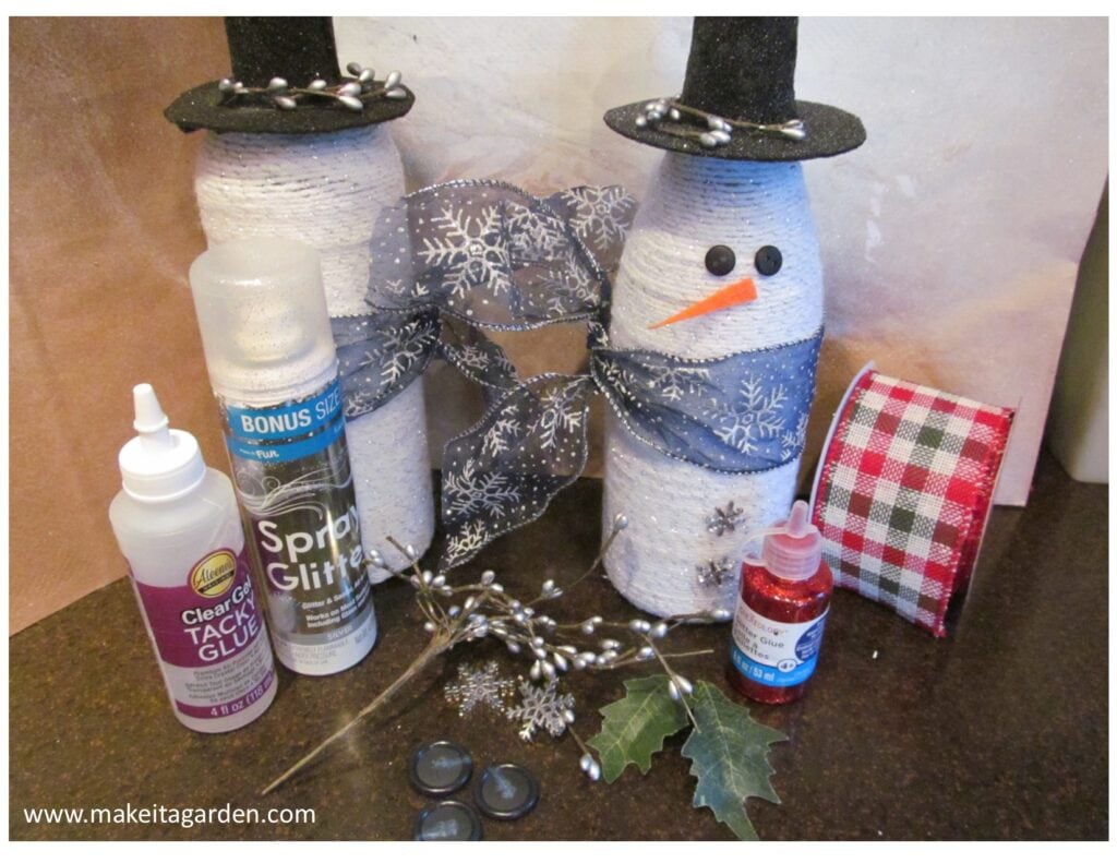 craft odds and ends collected together on the table to decorate and embellish the wine bottle snowman. Things like ribbon and glitter spray, twigs and buttons