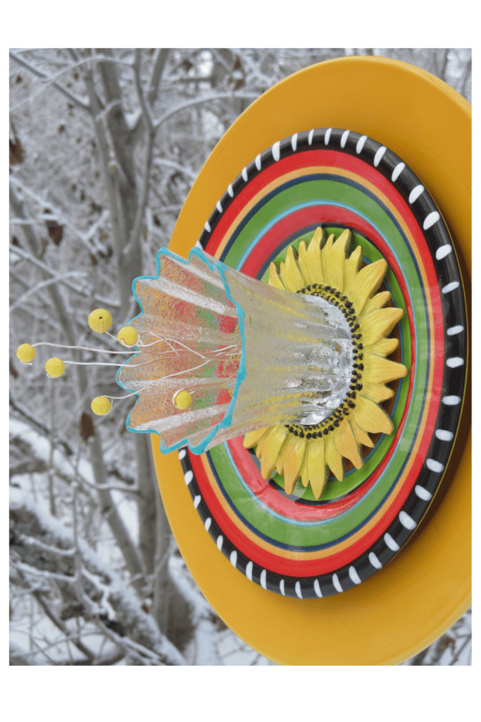 Colorful dinner plates glues together to look like a flower, The stamen mad with yellow beads, pop out of the center of this new dish flower design for the garden