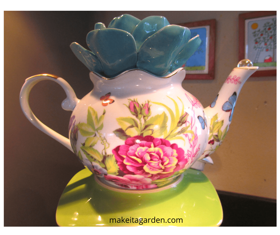 a very pretty decorative teapot with big, bright flowers and butterflies painted on it.