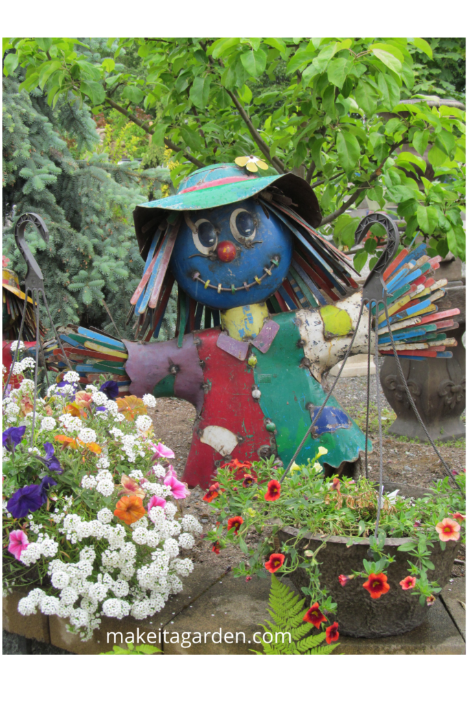 Large bright colored scarecrow lady made of scrap metal in the garden. Simple backyard art 
