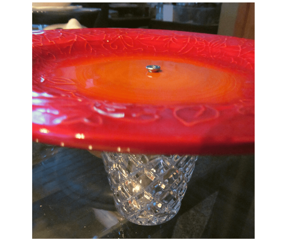 Ceramic plate with screw through laid on top of a glass vase used for a support stand