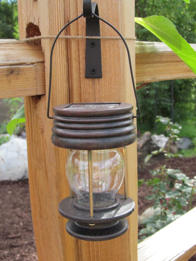 close up of a solar fairy lantern hanging on a wood fence post